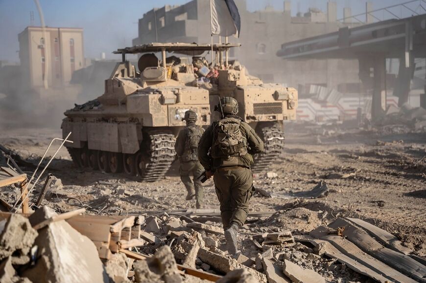A picture released by the Israeli army on July 22, 2024 shows Israeli soldiers behind an armoured vehicle during military operations in the Gaza Strip