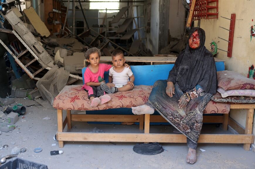 A woman wounded in an Israeli bombardment sits with children in Al-Bureij refugee camp in central Gaza