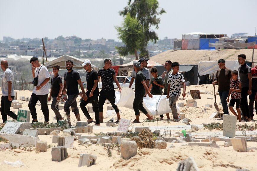 Palestinian volunteers exhume bodies from temporary graves at the Al-Amal Hospital in Gaza's second city of Khan Yunis for reburial by their families