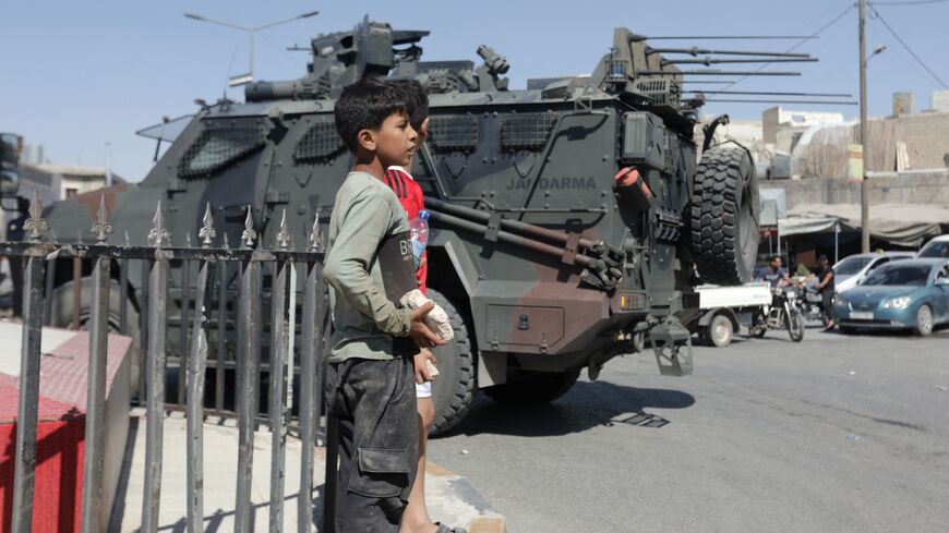Children watch as a Turkish armed forces vehicle drives during protests against Turkey in al-Bab, in the northern Syrian opposition held region of Aleppo, on July 1, 2024. 