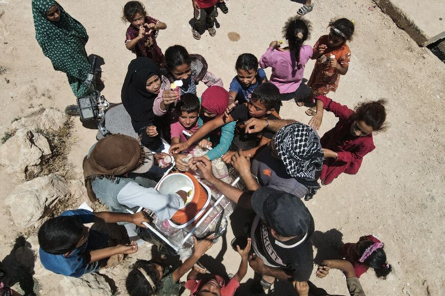 Syrian children gather to buy icecream from a vendor at a displacement camp