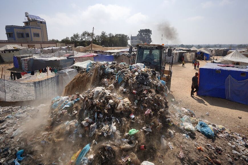 A bulldozer removes piles of garbage at a camp for displaced Palestinians in Deir el-Balah