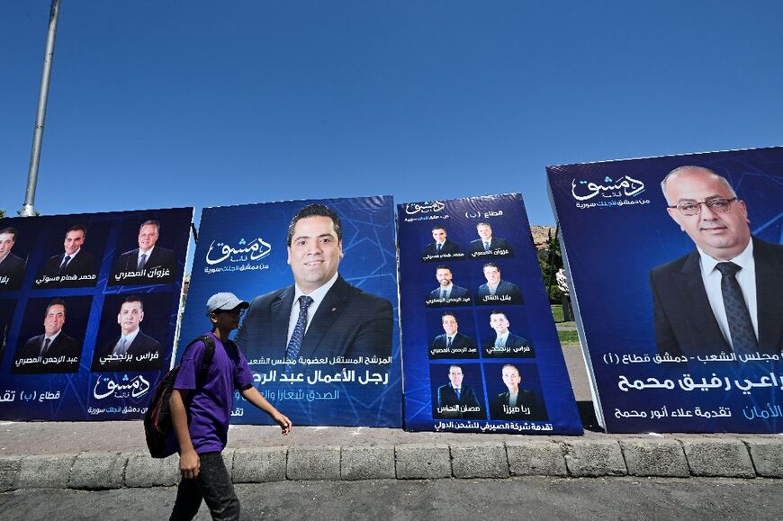 A young man walks past electoral campaign posters in Damascus a day ahead of parliamentary elections in government-held areas of Syria