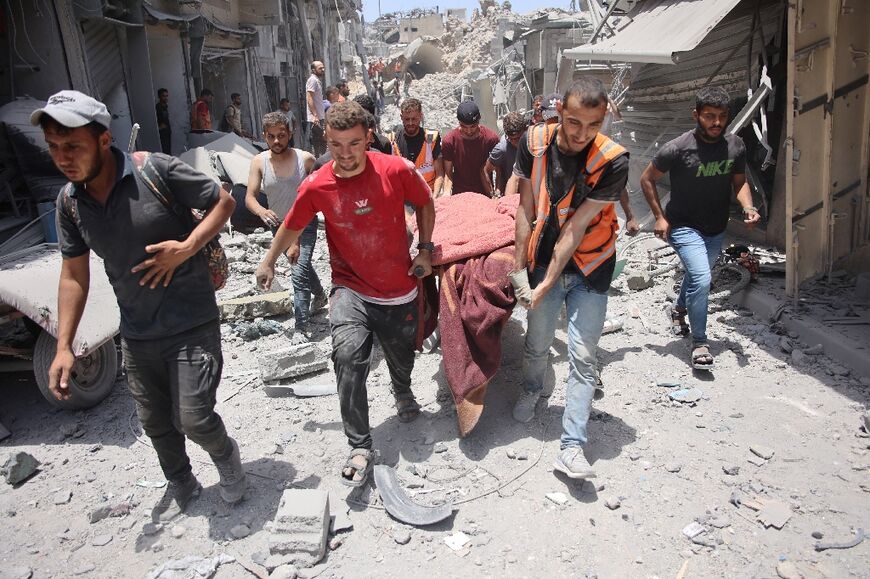 Palestinians carry a stretcher holding a body found in the rubble of destroyed buildings following bombardment in Gaza City