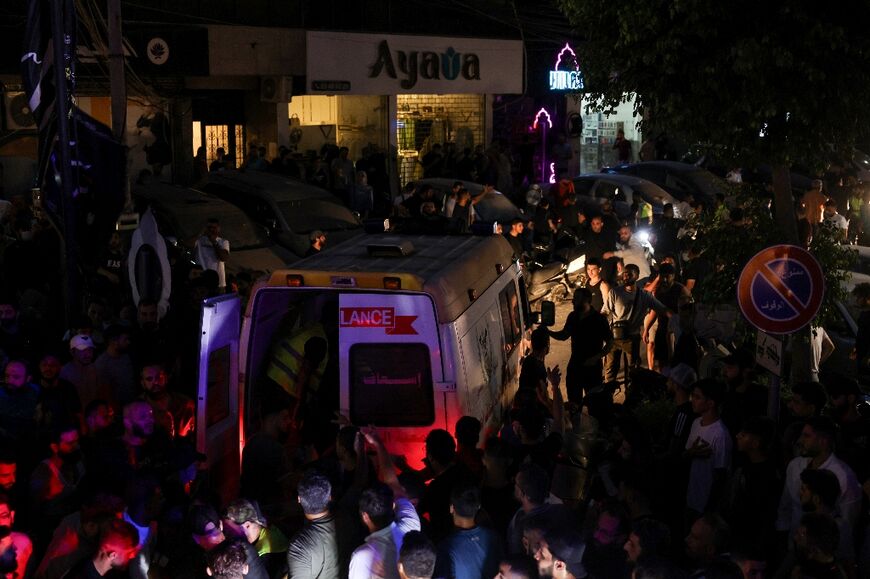 Bystanders surround an ambulance near the site of the Israeli strike in Beirut