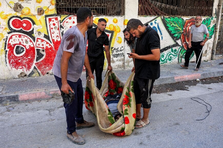 Men use a blanket to move a body found in Gaza City's Al-Tuffah district 