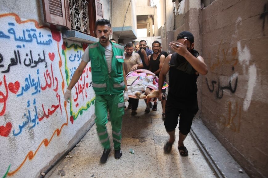 A body is carried on a stretcher from inside a residential apartment after bombardment of the Al-Daraj neighbourhood of Gaza City