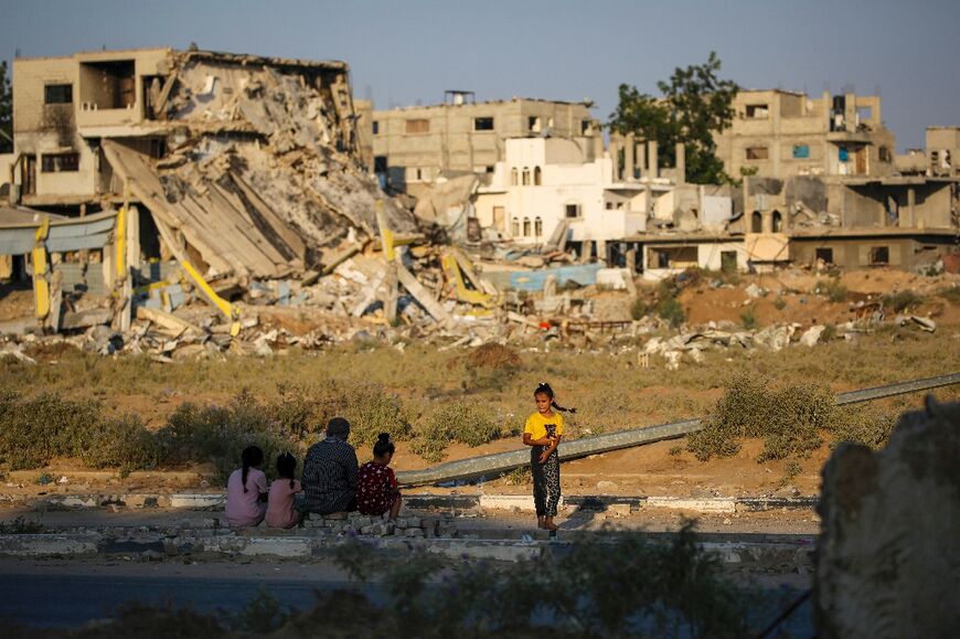 Palestinians sit near the rubble of buildings destroyed during Israeli bombardment in central Gaza's Al-Maghazi refugee camp