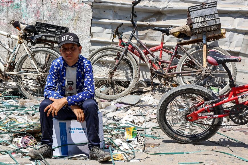 A boy sits atop a humanitarian aid package in Gaza City