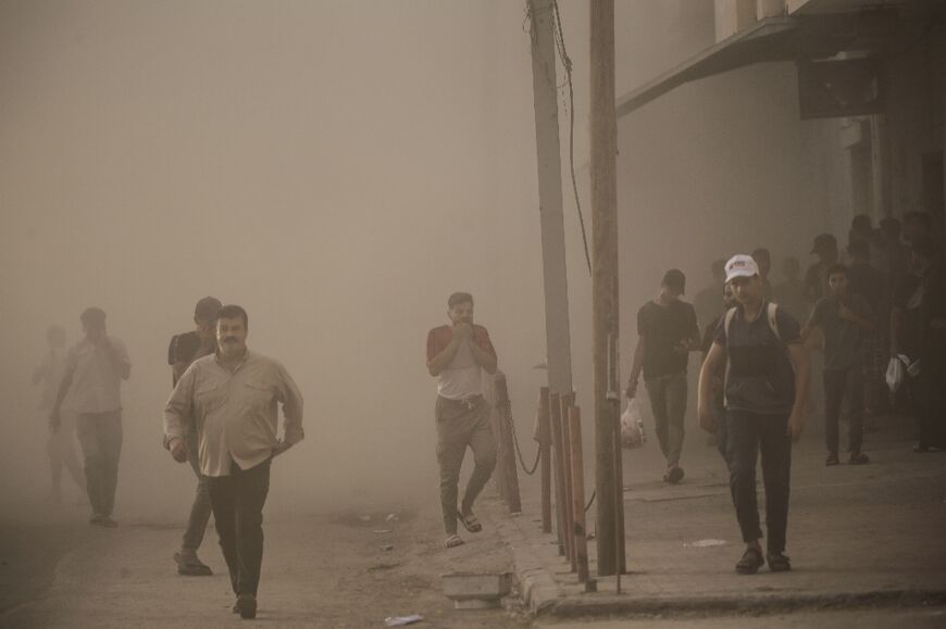 Palestinians engulfed by dust and smoke after Israeli forces targeted a building in central Gaza 