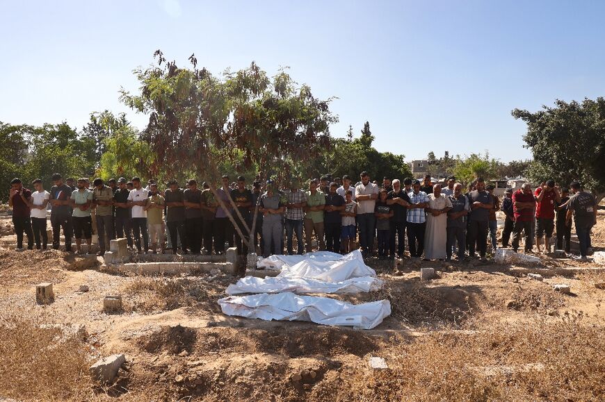 Palestinian men pray over the bodies of victims of Israeli bombardment in central Gaza