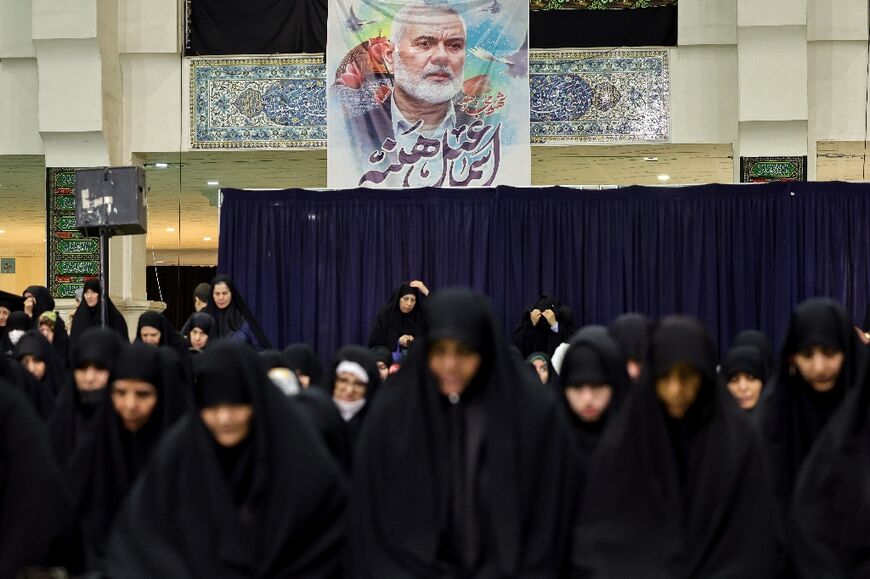 Iranians in Tehran attend a memorial ceremony for slain Hamas political chief Ismail Haniyeh, who is pictured on a banner