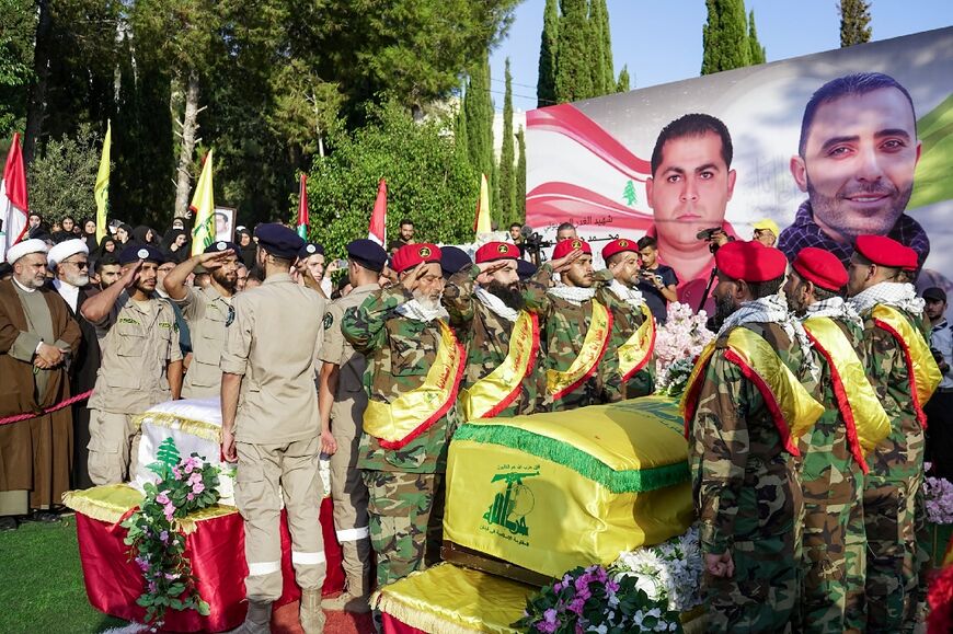 Hezbollah fighters and rescuers stand in salute at the joint funeral of a civilian and a fighter killed in an Israeli strike on the south Lebanon town of Jouaiya