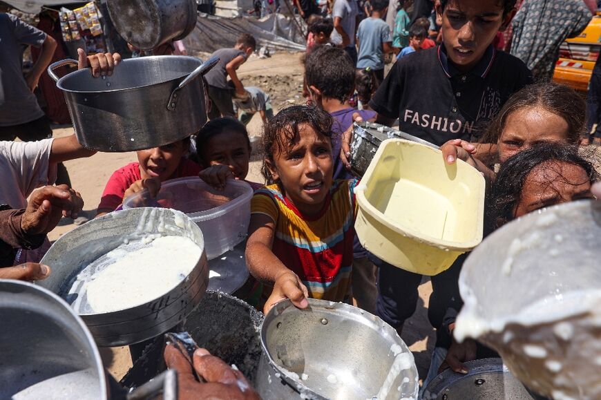 Displaced Palestinian children wait at a food distribution point in Deir el-Balah, central Gaza -- experts say hunger is rampant in the besieged territory