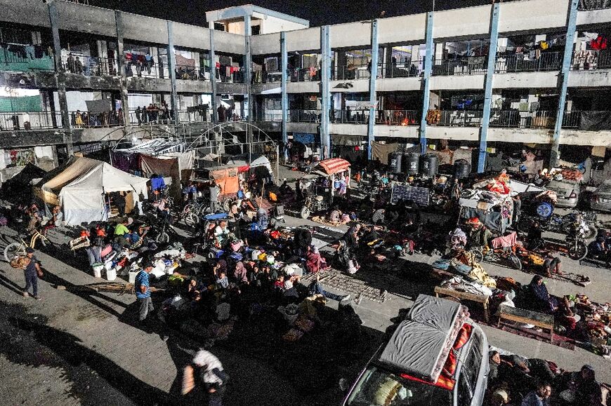 Displaced Palestinians who fled Gaza's main southern city of Khan Yunis in response to an Israeli evacuation order, prepare to spend the night in the courtyard of a UN school