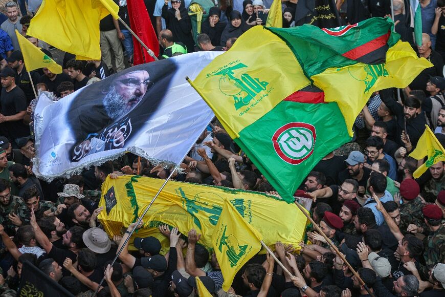 People wave flags at the funeral of top Hezbollah commander Fuad Shukr in Beirut's southern suburbs
