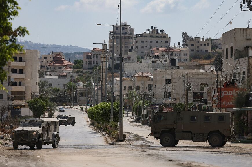 Israeli military vehicles roll down a street in Tulkarem, in the occupied West Bank's north