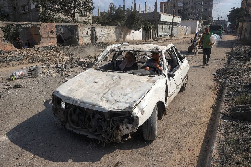 People flee in a damaged car from Nuseirat in the central Gaza Strip