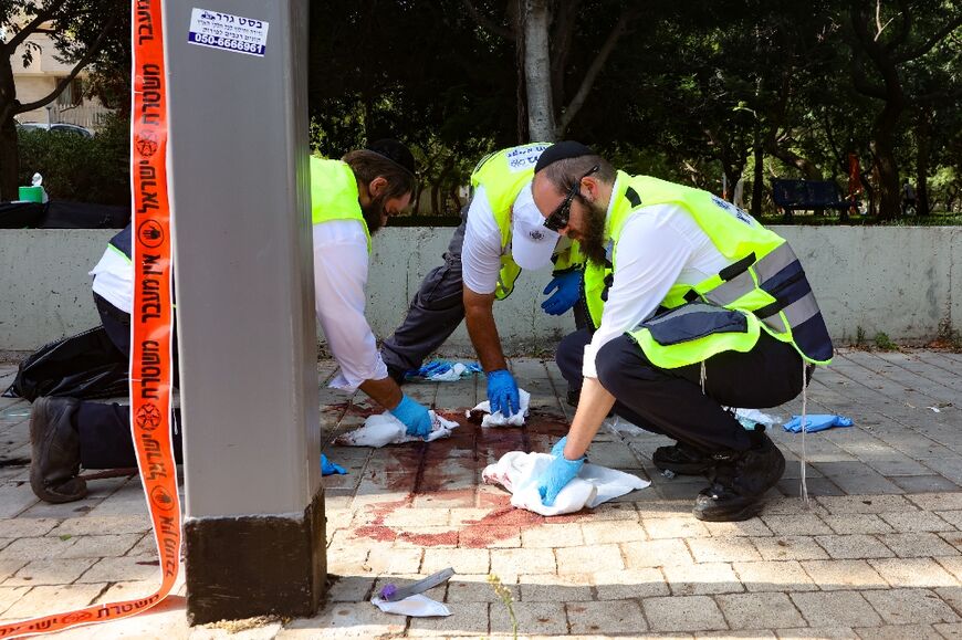 Israeli first responders scrub blood stains at the scene of a reported stabbing attack near Tel Aviv