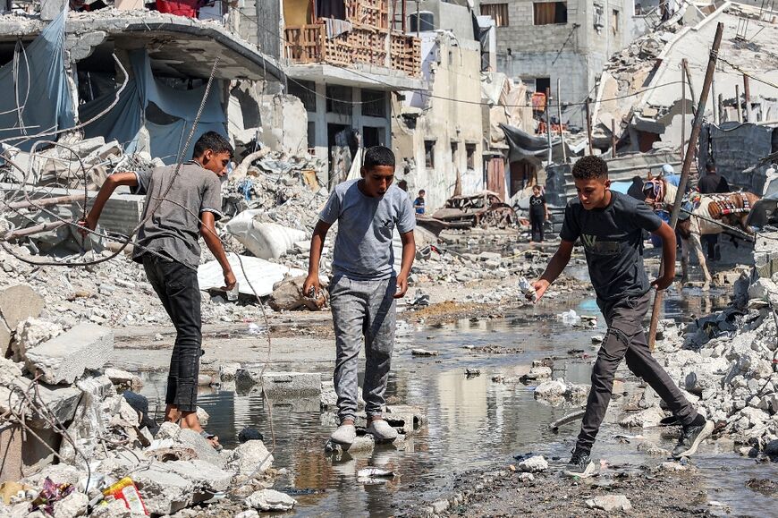 Palestinians cross a puddle of sewage water along a street in Gaza's Jabalia refugee camp