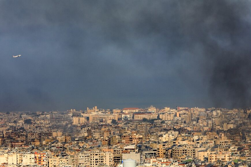 A Middle East Airlines commercial aircraft taking off from Beirut's international airport, flies amid smoke billowing above the Lebanese capital's southern suburbs, in the aftermath of overnight Israeli airstrikes