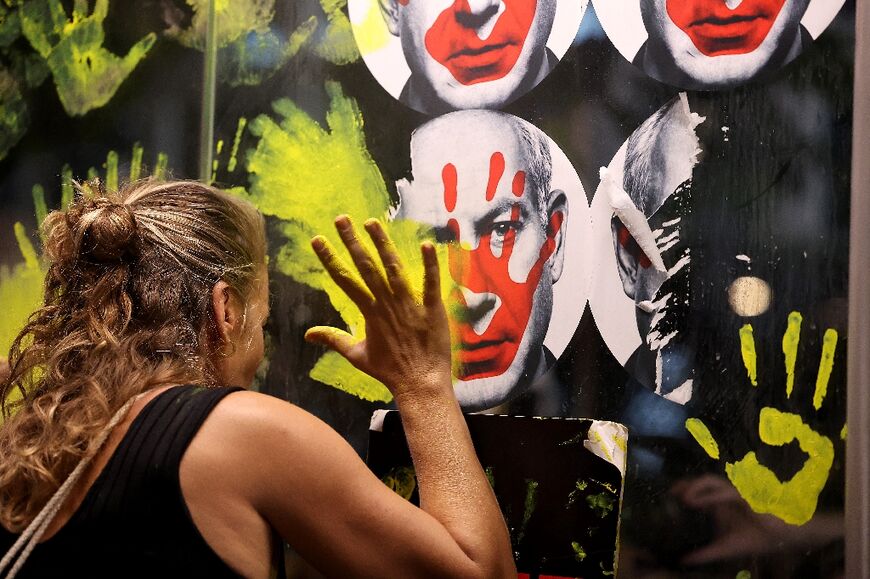 A woman defaces a picture of Benjamin Netanyahu as protesters demand action to secure the release of the hostages