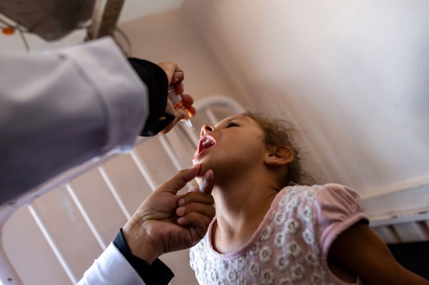 A nurse administers polio vaccine drops to a young Palestinian patient in southern Gaza's Khan Yunis