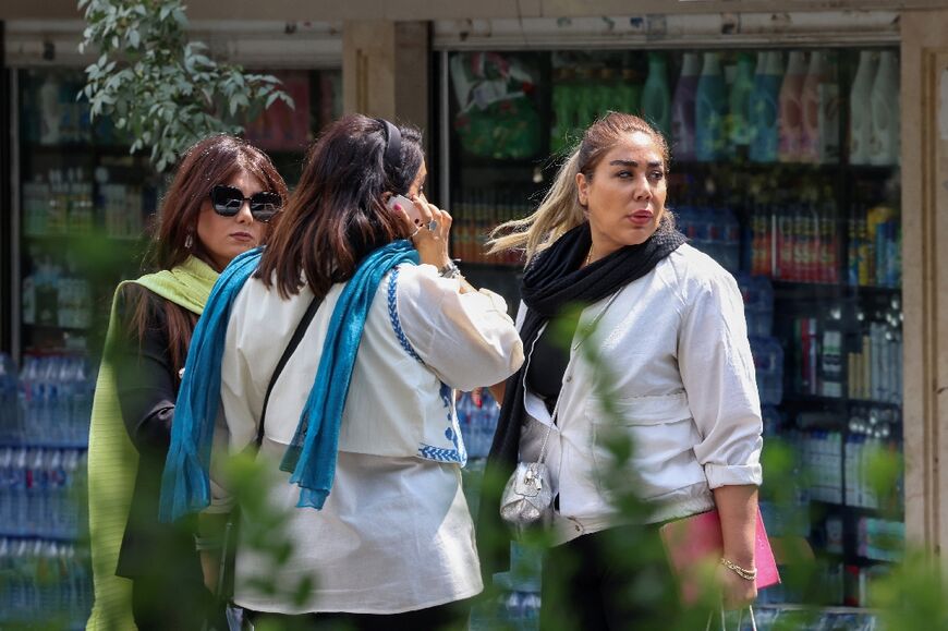 Women chat on a street in Tehran on the second anniversary of the protest movement