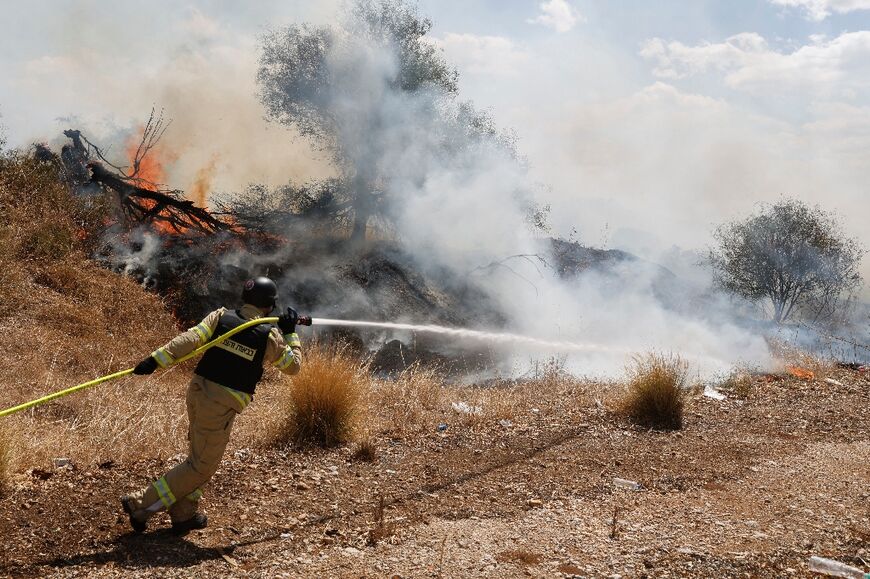 Firefighters douse flames in a field in Israel's north after a drone launched from southern Lebanon started a fire