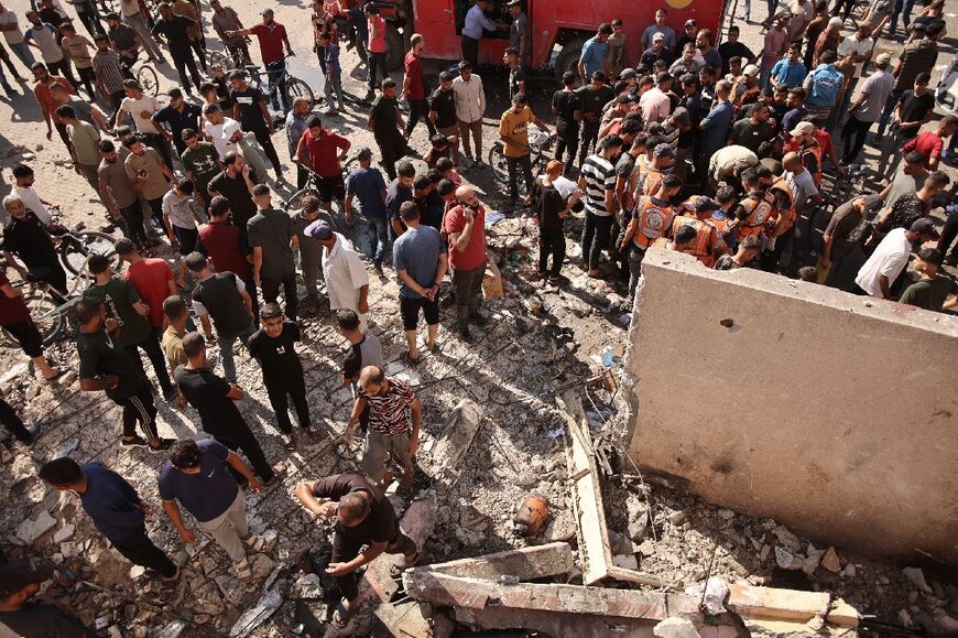 People and rescuers check the damage following an Israeli strike on a school sheltering displaced Palestinians in Gaza