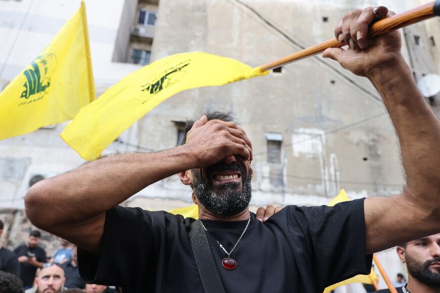 A Lebanese man clutching a Hezbollah flag is seen at funeral for people killed in pager attacks