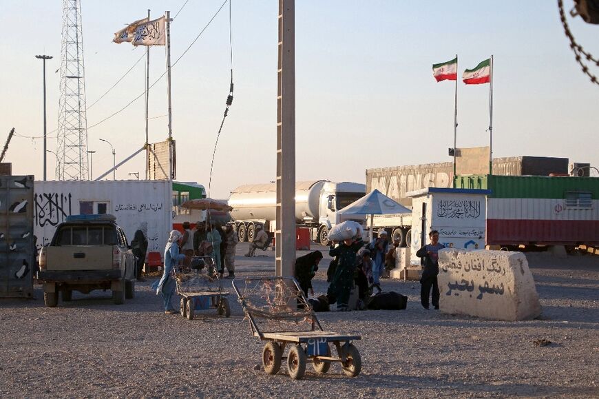 Taliban (L) and Iranian (R) flags are pictured at zero-point near the Afghanistan-Iran border in the Islam Qala district of Herat province