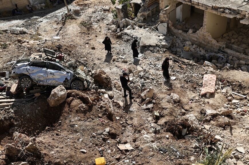 People examine the destruction in the aftermath of an Israeli military raid in Qabatiyah