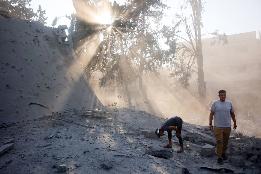 A Palestinian man searches for victims or survivors through a hole in a bombarded building in Gaza City