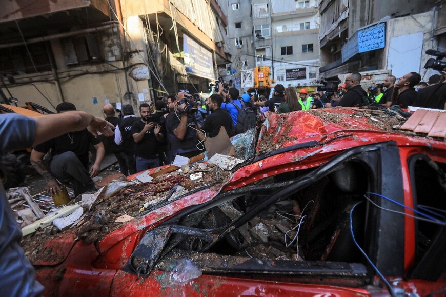 Bystanders and reporters check the destruction in a street under a residential building whose top two floors were hit by an Israeli strike in the Ghobeiri area of Beirut's southern suburbs on September 24, 2024