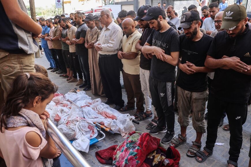 Palestinian men pray over the bodies of victims of Israeli bombardment in central Gaza's Nuseirat