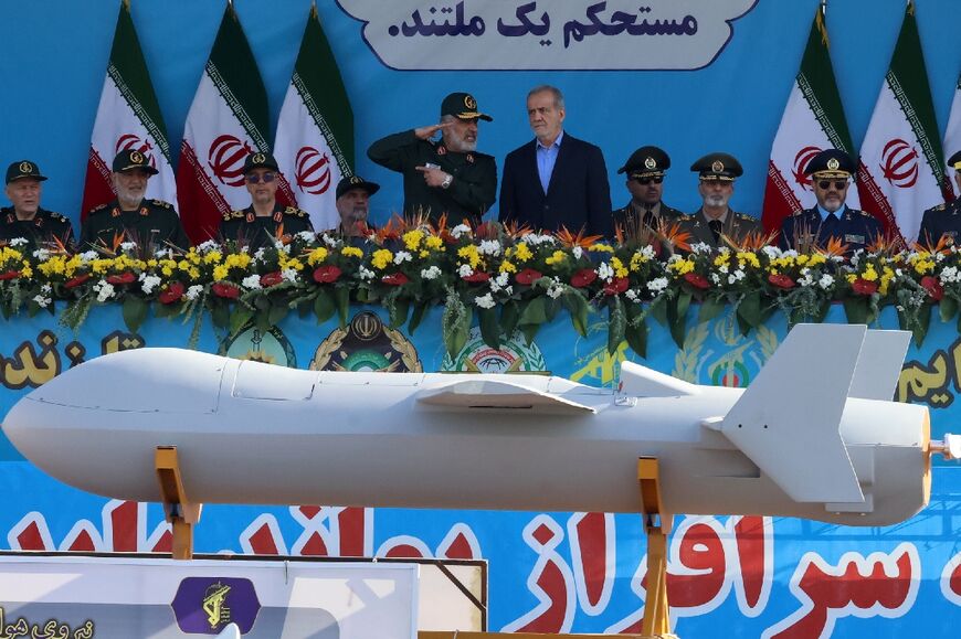 Revolutionary Guards aerospace chief Amir Ali Hajizadeh (L) briefs President Masoud Pezeshkian as Iran shows off an upgraded one-way attack drone