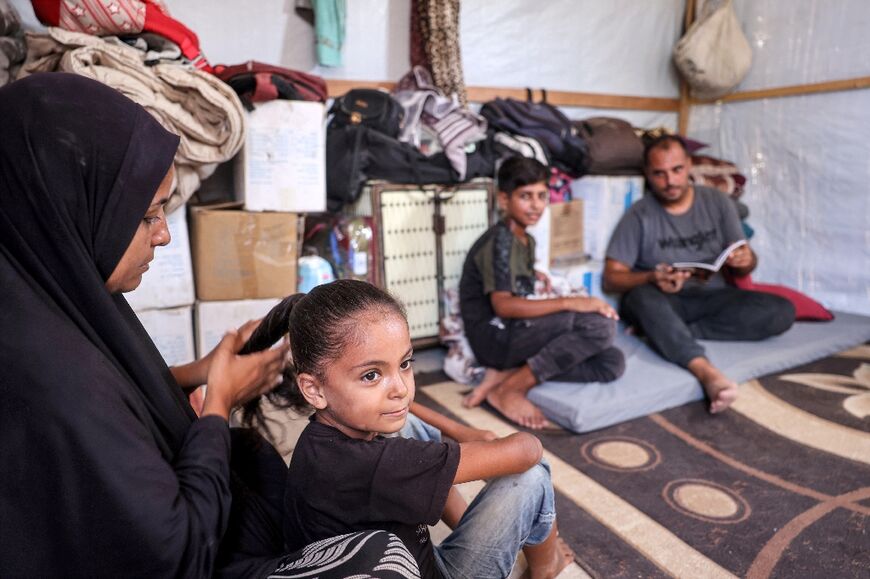 Fatima Khudeir, 33, braids her daughter's hair as she sits near her husband Maher