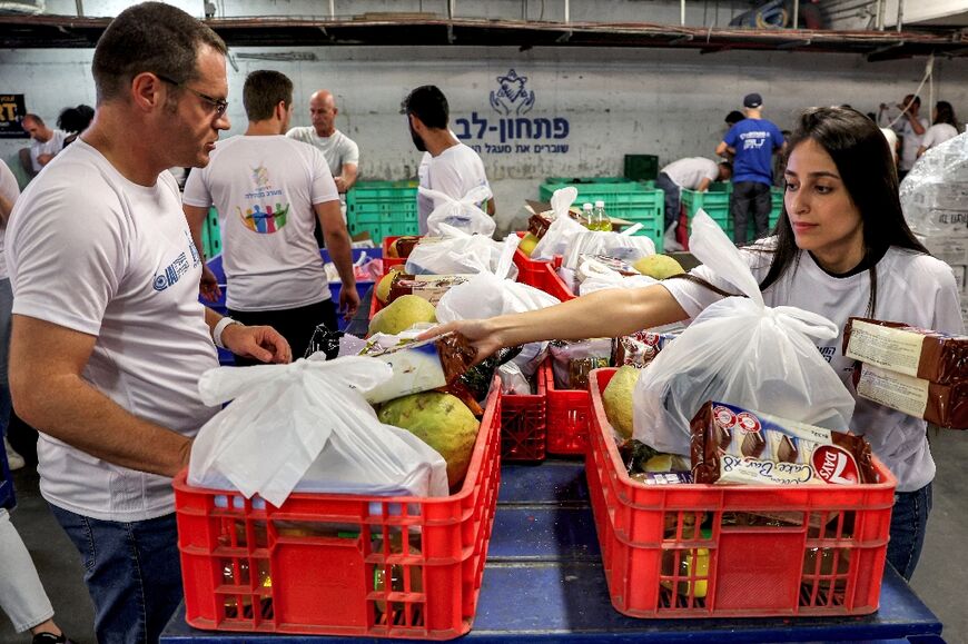 Israeli volunteers distribute food bags to people in an underground parking lot in Rishon LeZion