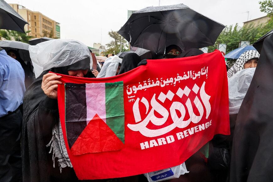 Women demonstrators hold a banner showing a Palestinian flag and the Arabic word "revenge" during an anti-Israel protest in Iran