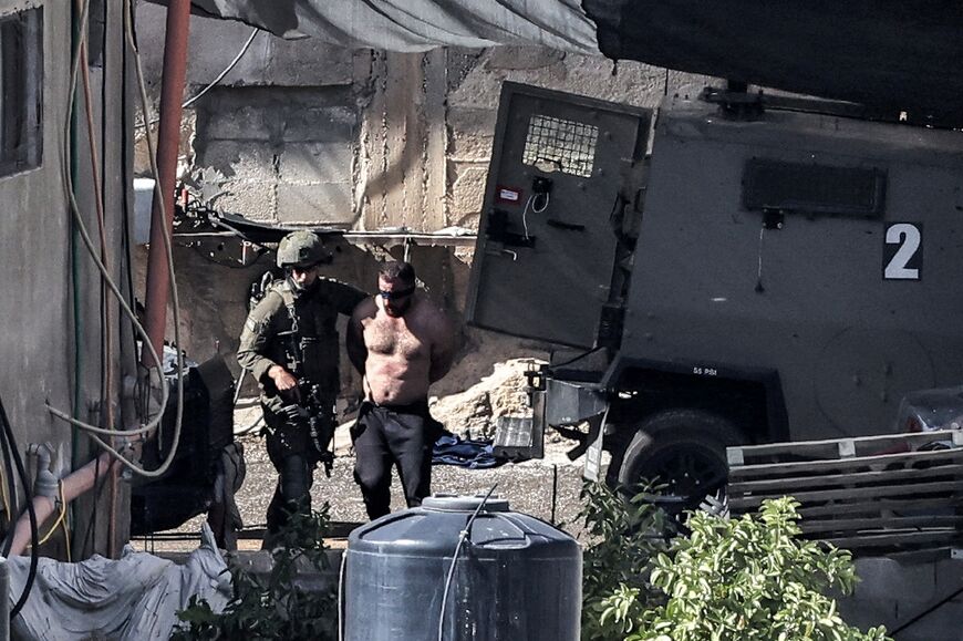 Israeli soldiers detain a man during the raid in Qabatiya