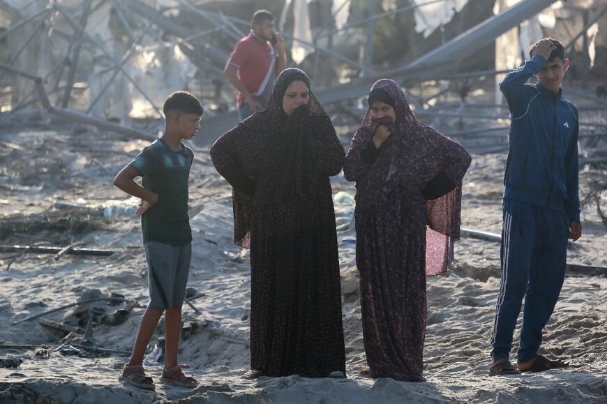 Women and children inspect the damage after strikes at the Al-Mawasi camp