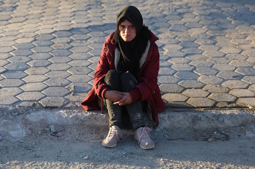 A displaced Palestinian, ordered by the Israeli army to leave the school in Beit Lahia where they were sheltered, rests as she arrives in Gaza City