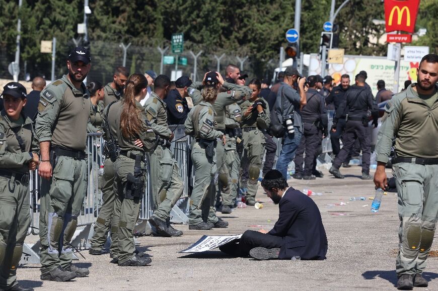 An Ultra-Orthodox protester sits on the ground outside the Tel HaShomer army base near Tel Aviv during the August protests