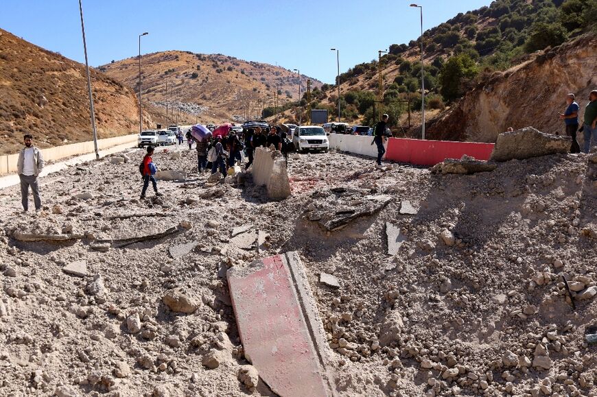 Refugees from the violence in Lebanon continue their journey to the Syrian border on foot after running into a section of highway blocked by damage from an Israeli strike