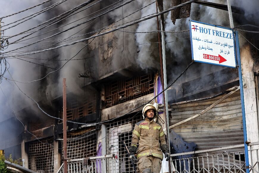 A first responder stands in front of a building set on fire by an Israeli strike that targeted Beirut’s southern suburbs on October 6, 2024