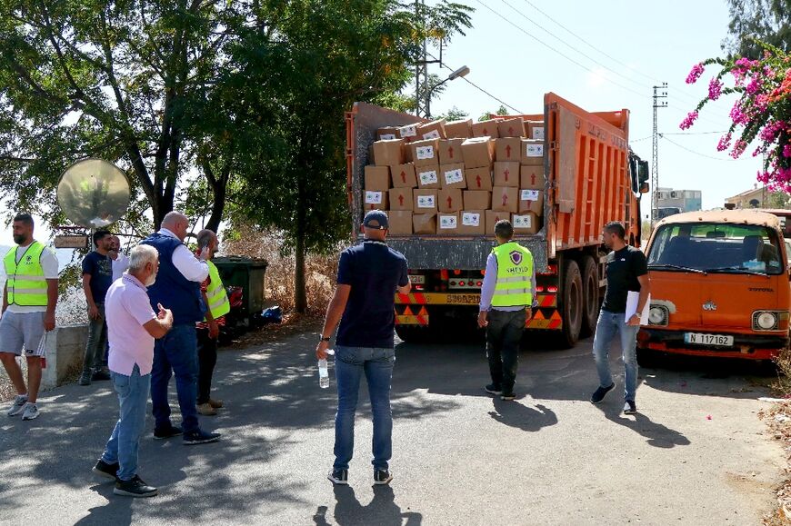 Volunteers and residents wait near a truck carrying humanitarian aid from NGOs through the Lebanese Ministry of Social Affairs, in Qlayaa, southern Lebanon