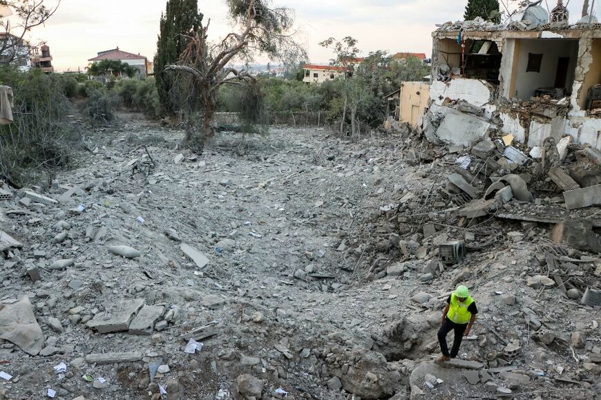 A rescuer stands in the rubble of a building destroyed in an Israeli air strike on the southern Lebanese village of Hanouiyeh