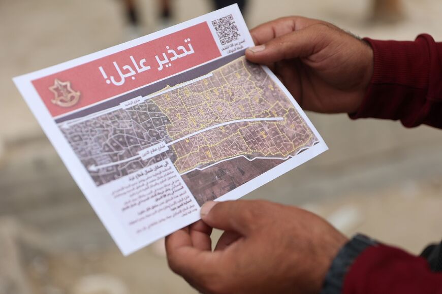 A man examines a flyer dropped by Israeli aircraft ordering Palestinians to evacuate the Jabaliya area