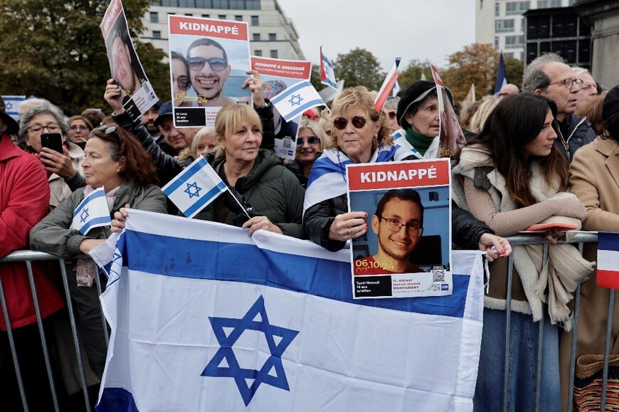 People hold Israeli flags and a portrait of hostage Tamir Nimrodi at a commemoration in Paris